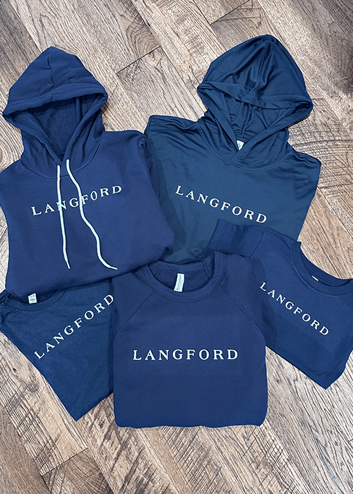 Five navy blue Langford brand sweatshirts and hoodies arranged on a wooden floor.