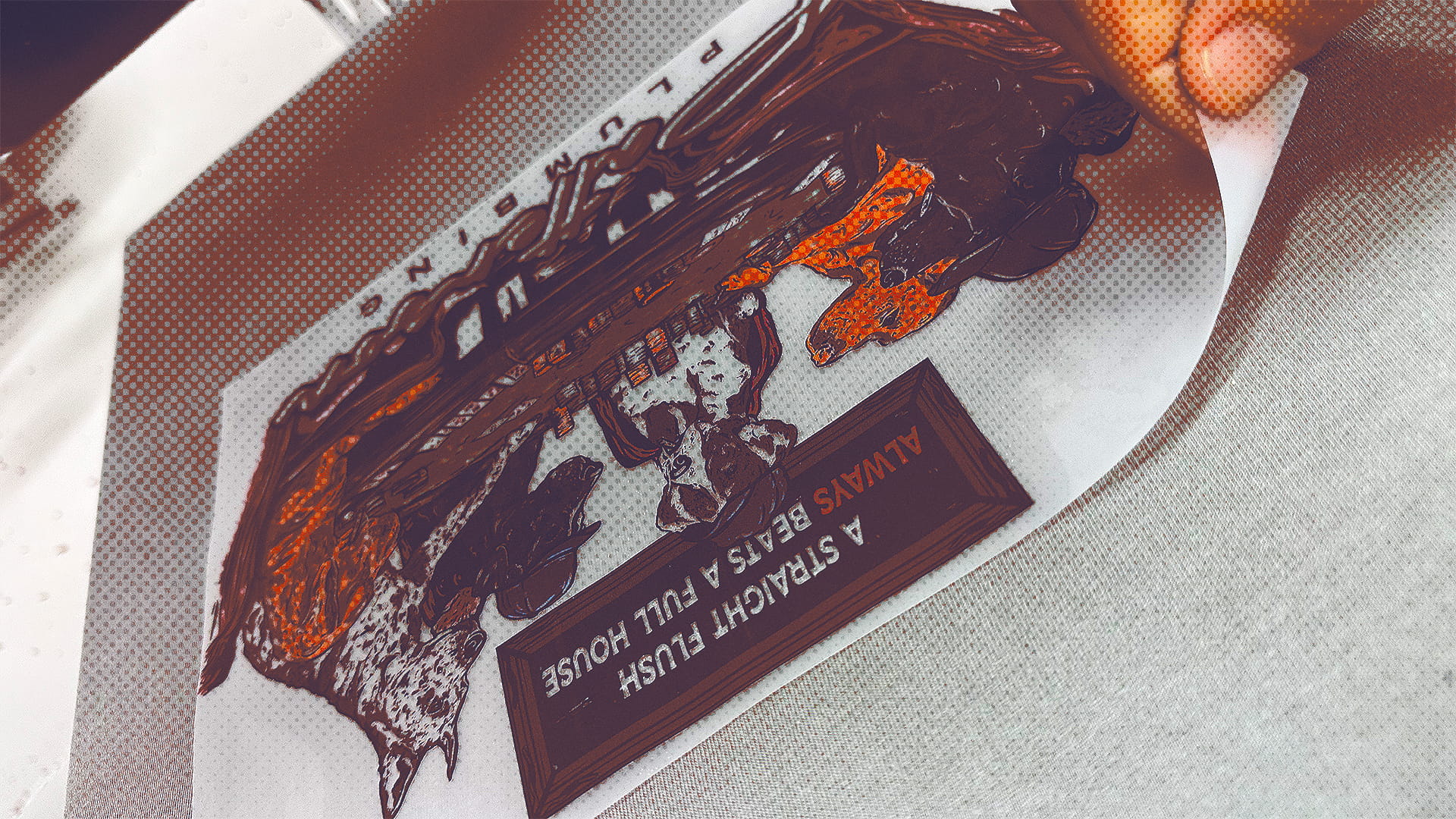 Hand peeling back a heat transfer sticker featuring a design with three fish and the text 'A STRAIGHT FISH ALWAYS BEATS A FULL HOUSE.'