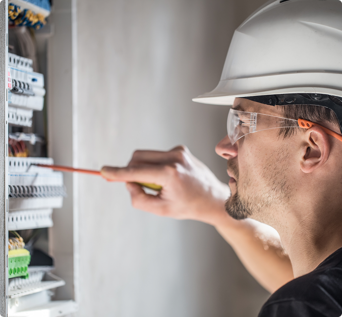 Elektroniker mit Schraubendreher arbeitend in einem Schaltschrank
