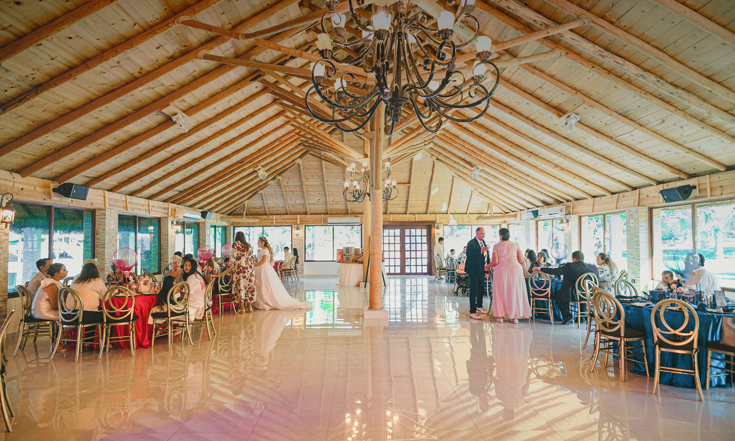 Bright, sunlit event venue table setting with turquoise plates and rattan chairs