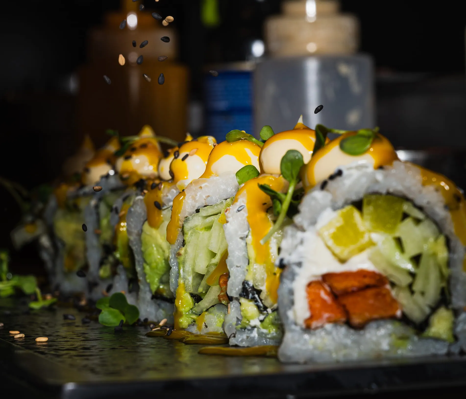 Detaillierte Nahaufnahme von Sushi-Rollen mit Gurke, Avocado, Sauce und Sesamsamen.