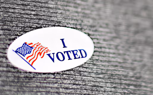 An I Voted sticker close up on a gray sweater