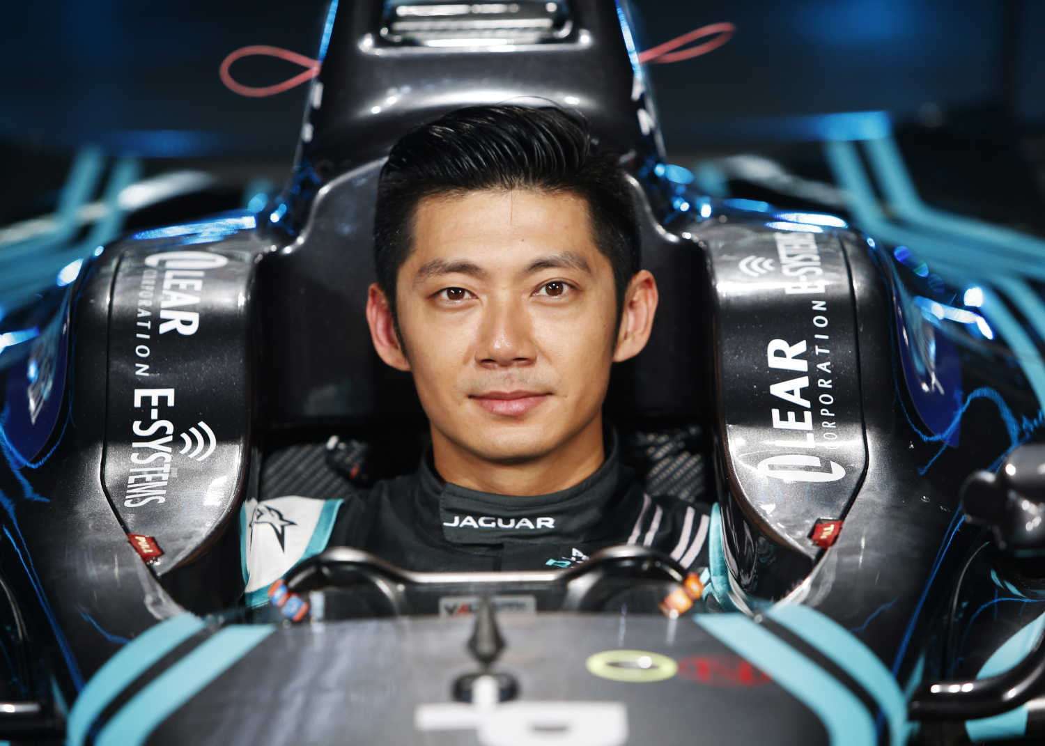 Race car driver seated in a Jaguar Formula E racing car cockpit.