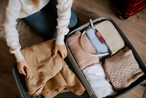 A person organizing clothes into a suitcase