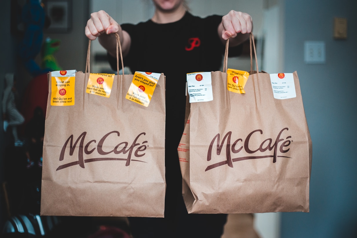 A person holding up two McCafe bags