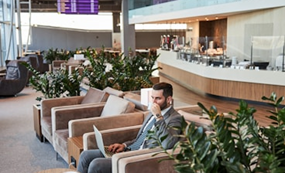 Lounge area with a man sitting on a sofa using a laptop