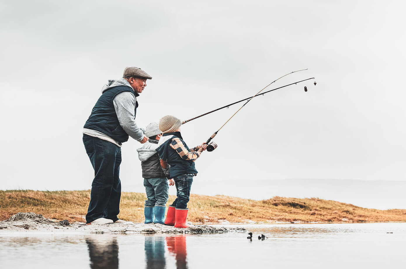 Grandfather teaching two young children to fish by the water, representing Cornerstone Financial Planning’s focus on family values, legacy, and long-term financial guidance.