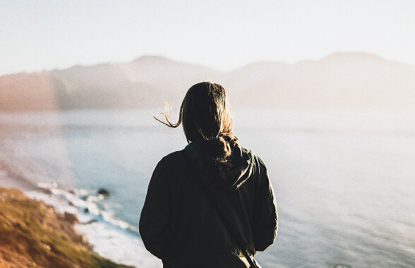 Woman overlooking ocean cliffs, representing financial planning that incorporates purpose, reflection, and long-term values.