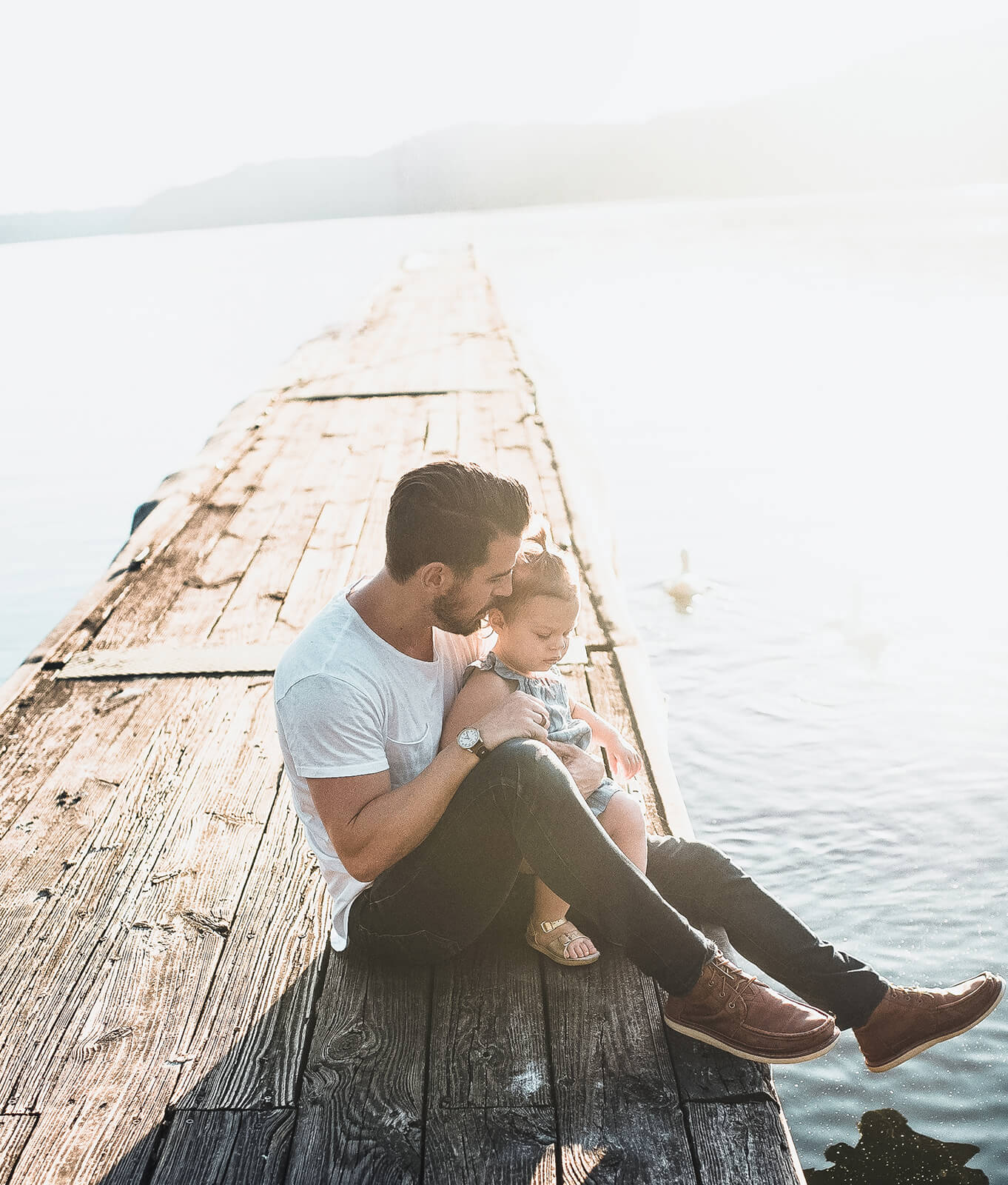 Father and child sitting together on a dock, symbolizing secure financial planning and long-term wealth management for families in Portland, ME & Portsmouth, NH