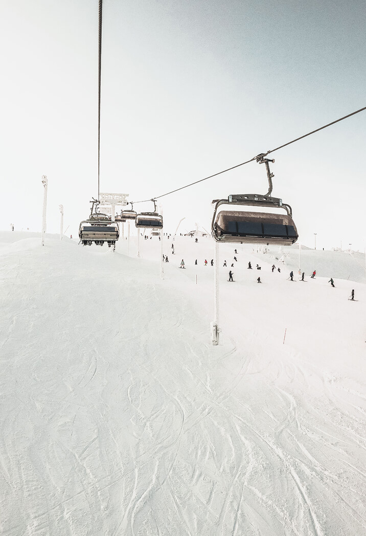 Ski lift carrying skiers up a snowy mountain, illustrating preparation and strategy in financial planning for life’s ups and downs.