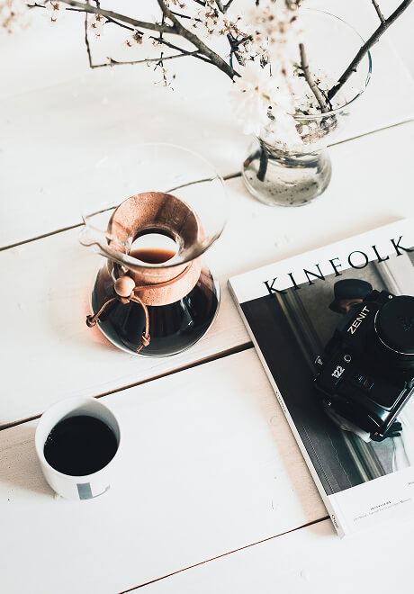 Coffee and open book with flowers on a white table, representing clarity, focus, and thoughtful financial planning.