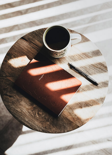 Coffee and notebook on wooden table, representing thoughtful, personalized financial planning with Cornerstone advisors.