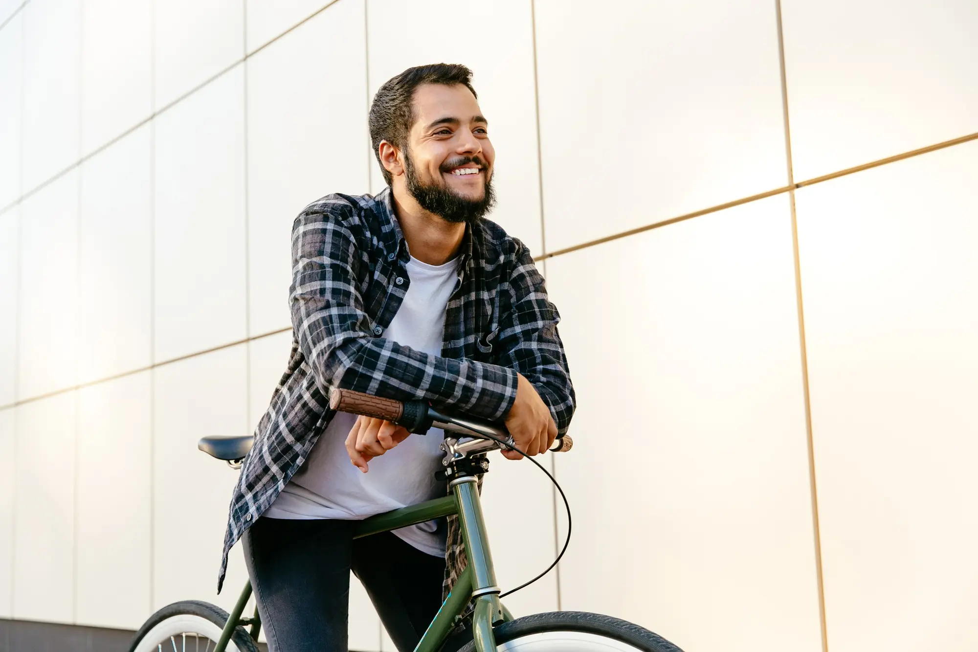 Young man in recovery standing with a bicycle, representing healthy routines and support from a recovery coach