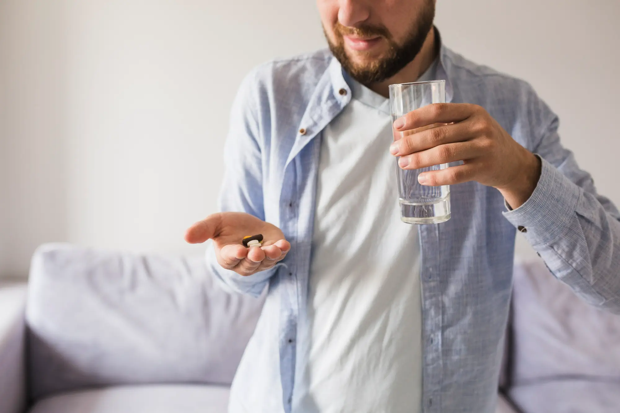 Man taking prescribed medication with water during medication-assisted treatment for substance use recovery