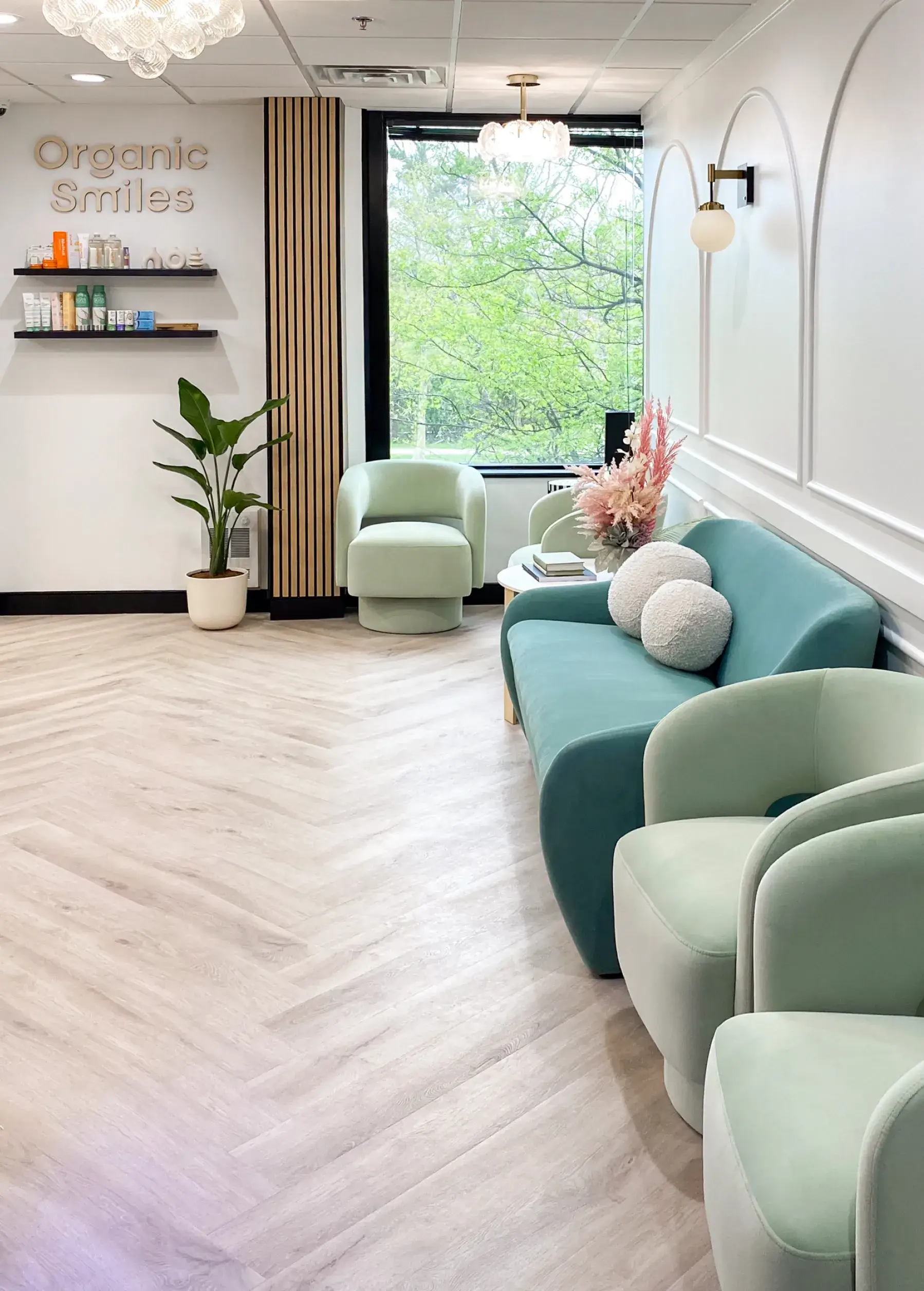 A bright waiting room with green chairs, a couch, and a shelf with dental products.
