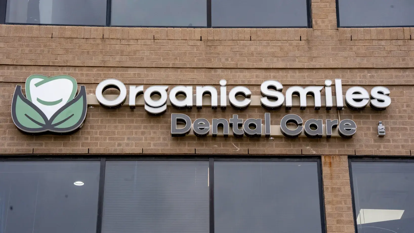 Sign for "Organic Smiles Dental Care" on a brick building.