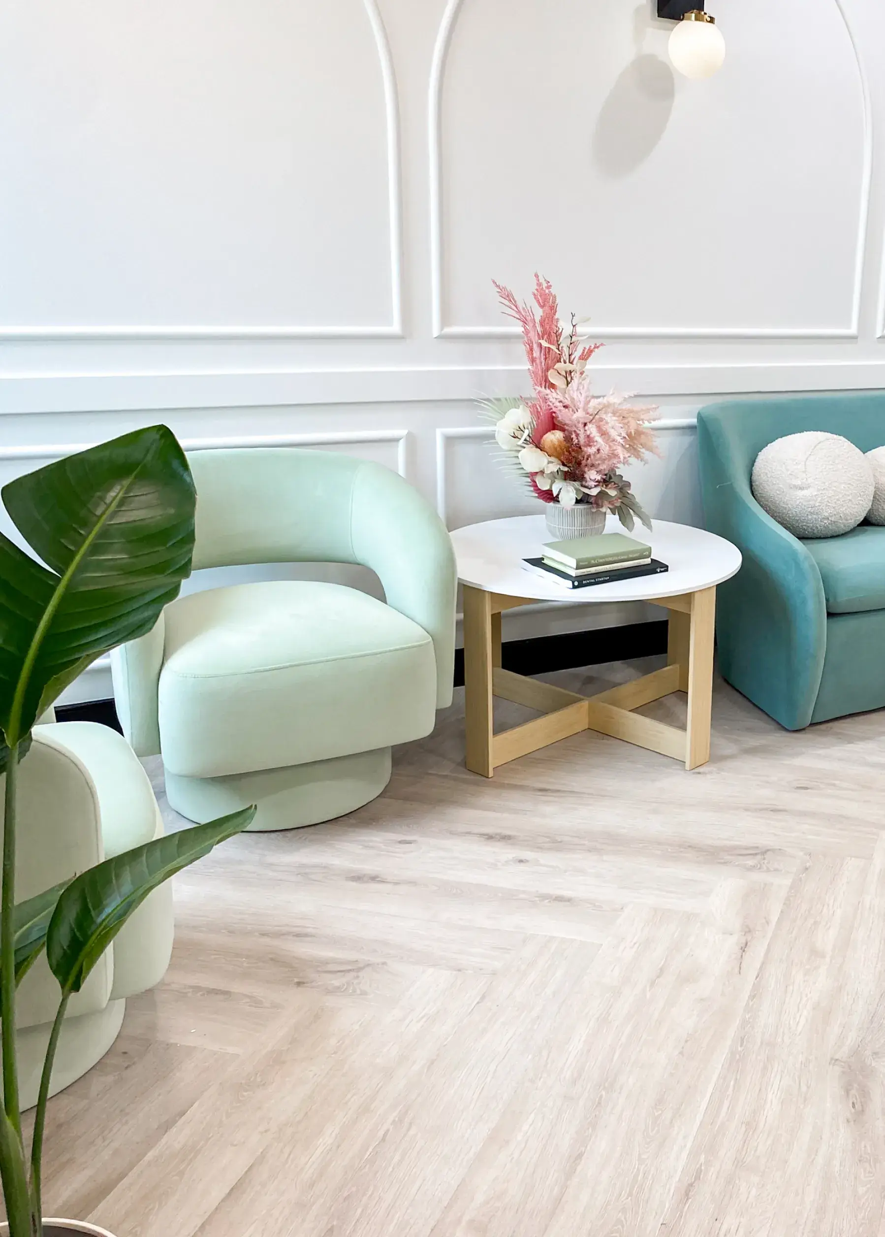 A cozy seating area with mint-green chairs and a small table with flowers and books.