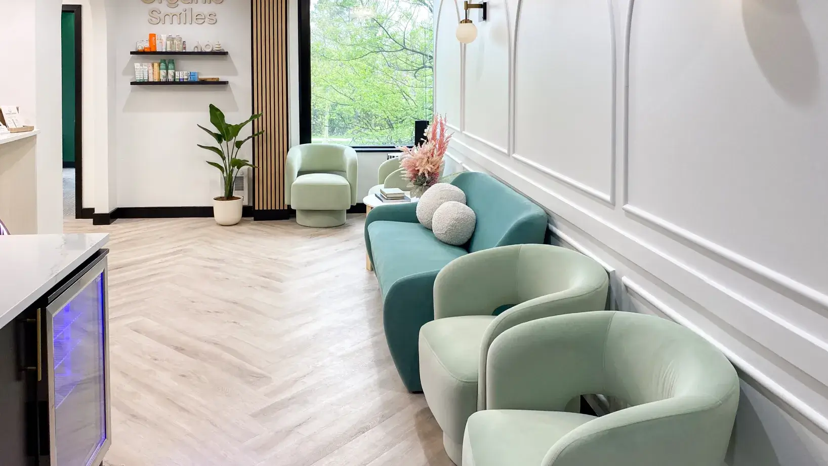 A modern waiting area with light blue chairs and a blue sofa, next to a large window.