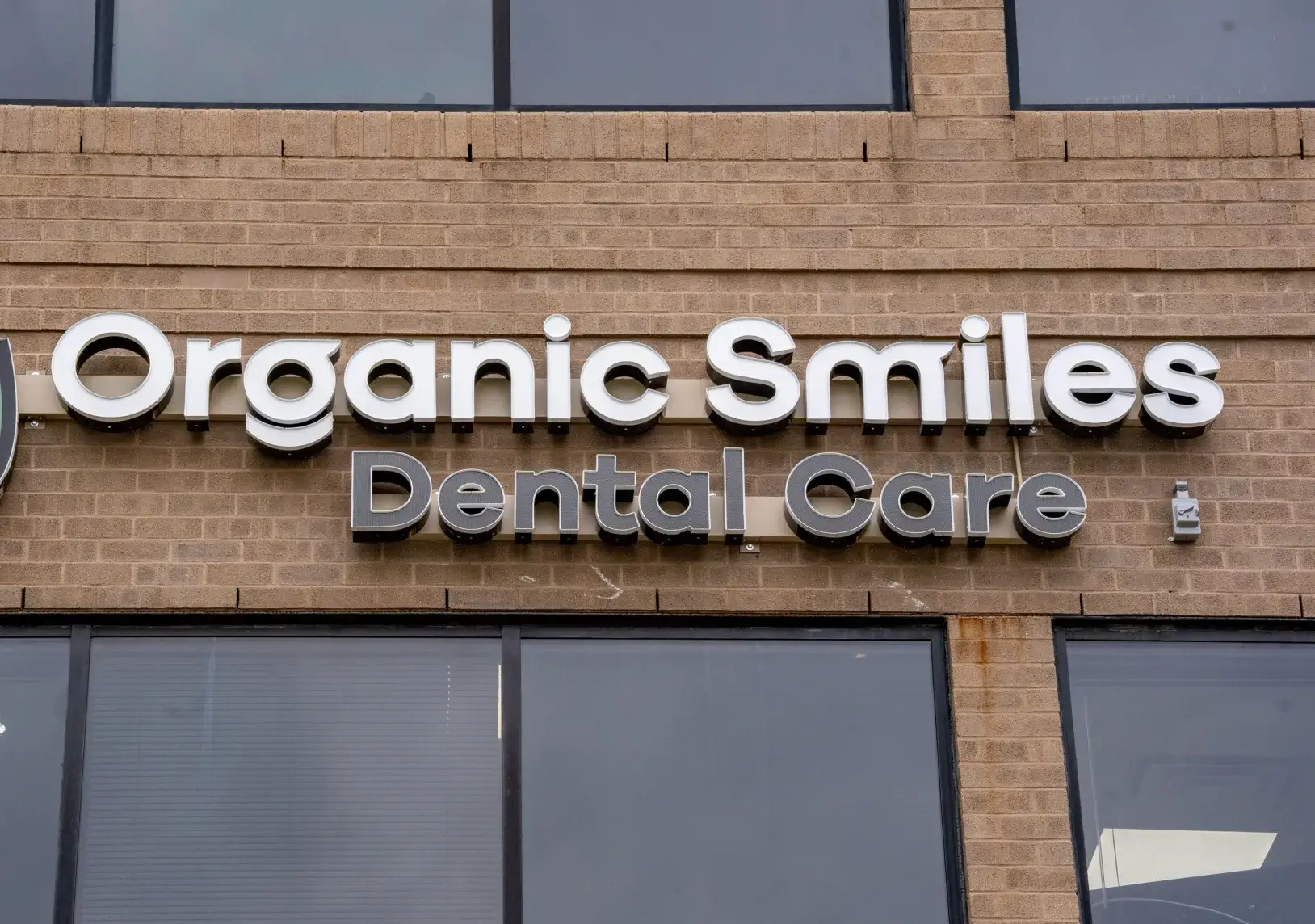 Sign on a brick building reads, "Organic Smiles Dental Care" in large white letters.