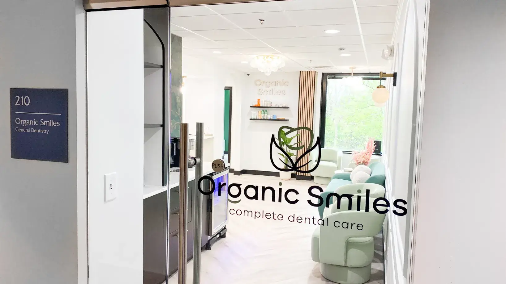 Dental clinic entrance with "Organic Smiles" logo on the glass door, leading to a waiting area.