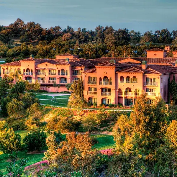 Aerial view of the Fairmont Resort Property with terracotta roofs surrounded by landscaped greenery and trees under a clear sky.