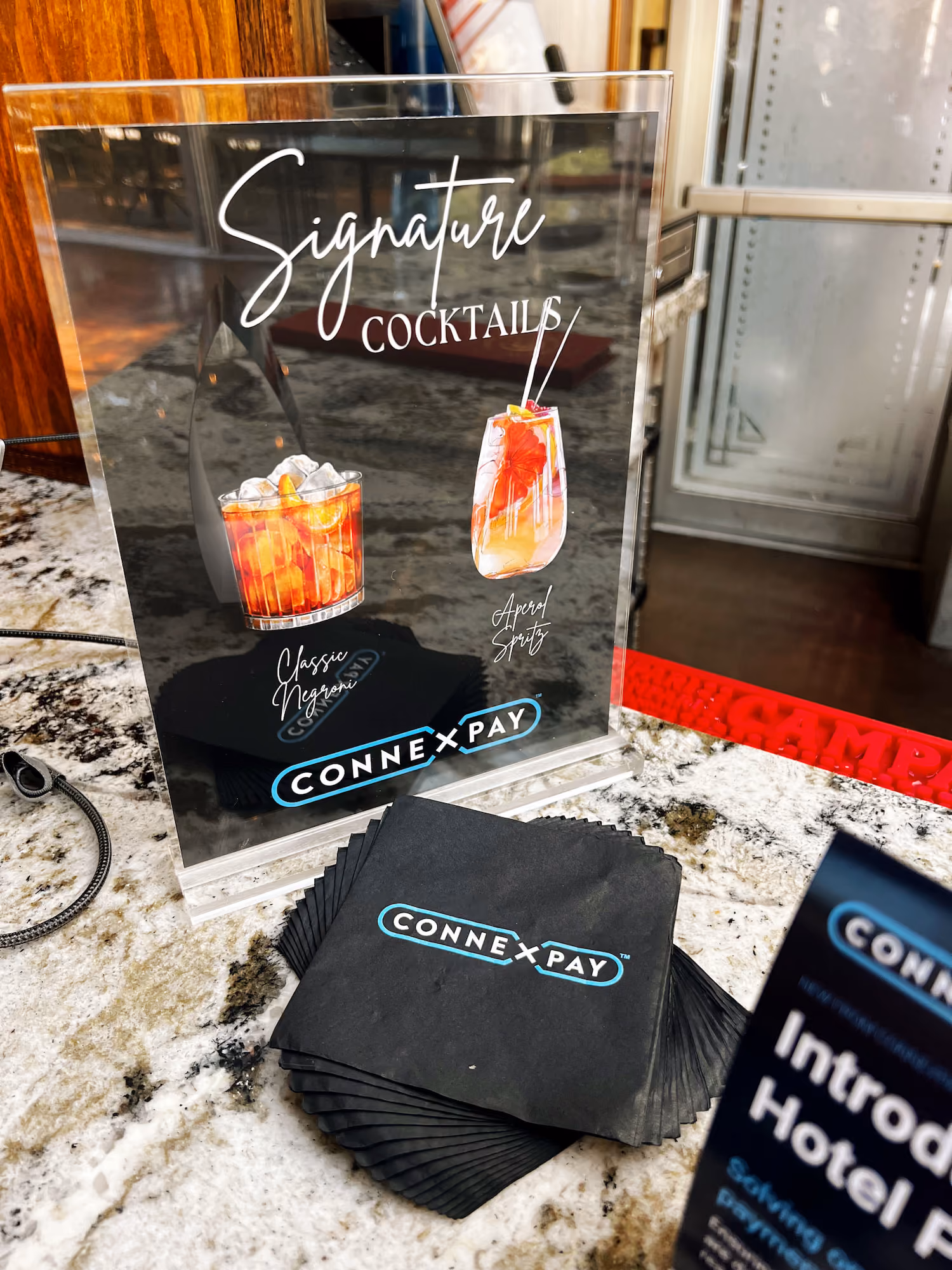 Clear sign on marble counter shows Signature Cocktails with Classic Negroni and Aperol Spritz drinks.