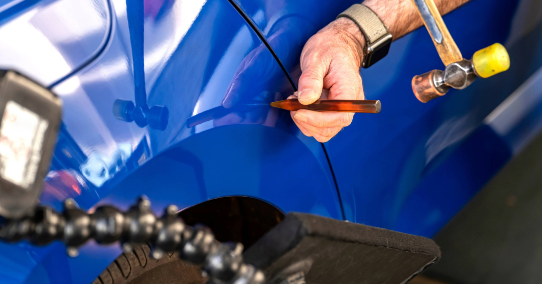 Paintless dent repair technician fixing minor dents and hail damage on vehicle door in Fishkill NY without repainting.