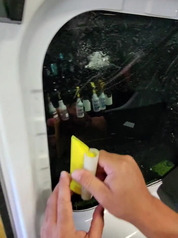 Hands working window tint against rear glass at KOD