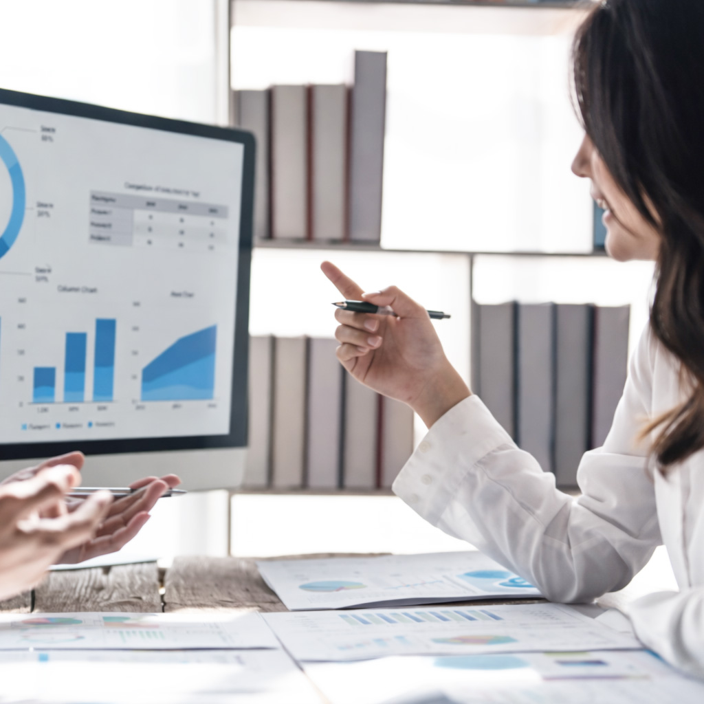 Woman presenting financial charts and graphs on a computer screen during a business meeting