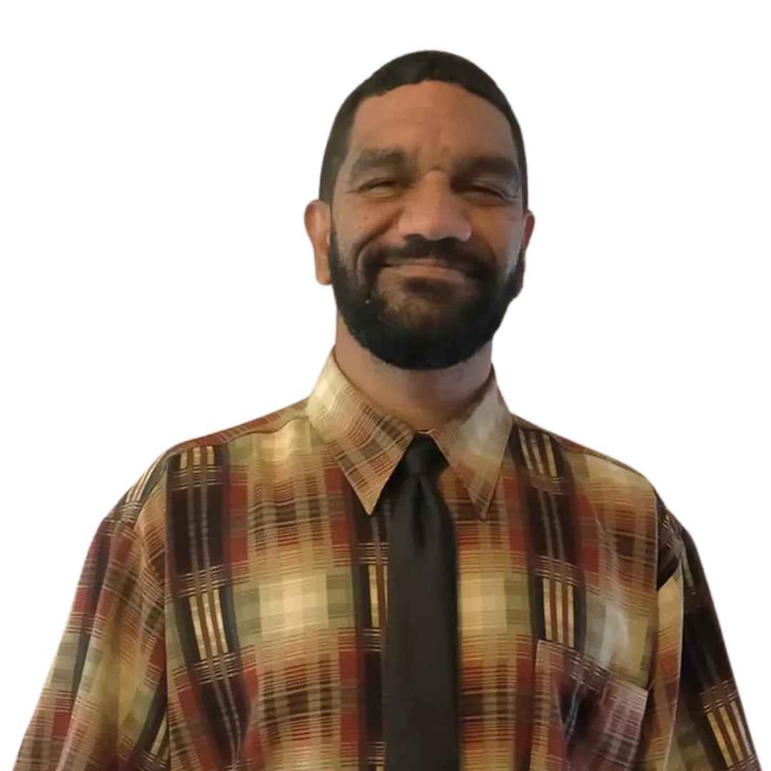 Man with short hair and beard smiling, wearing a multicolored plaid shirt and a black tie.