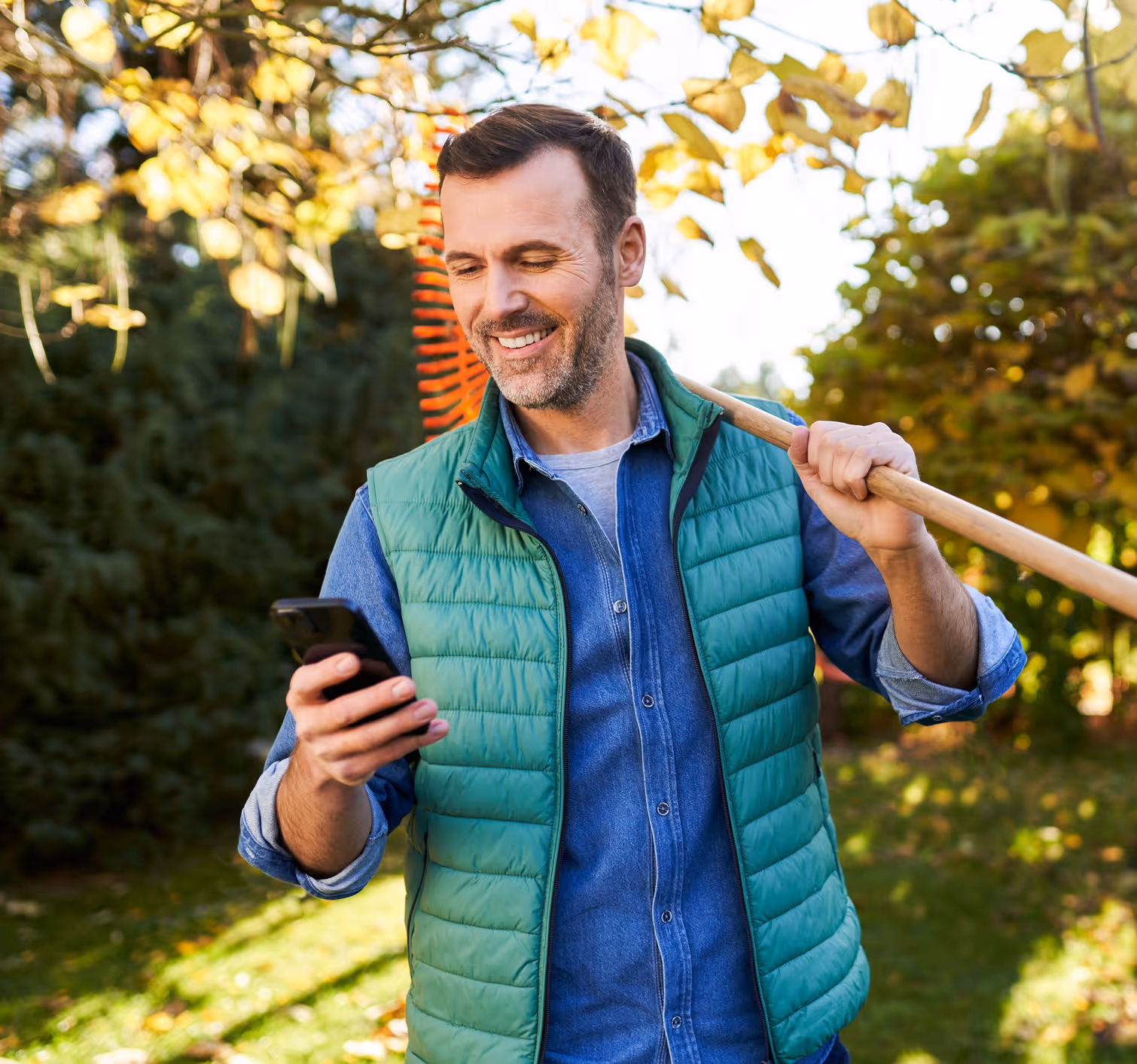 man holding a phone with a rake on his other hand