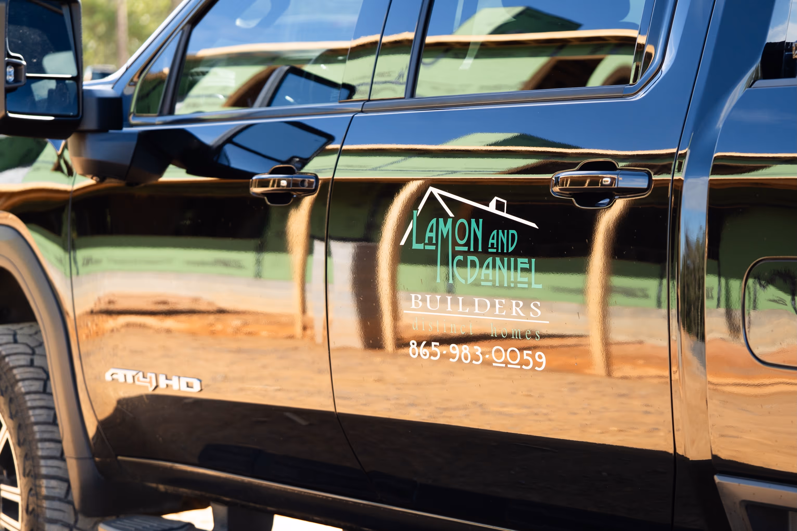 White two-story house with a porch, steps, and greenery in front, with a green vintage truck partially visible in the foreground.
