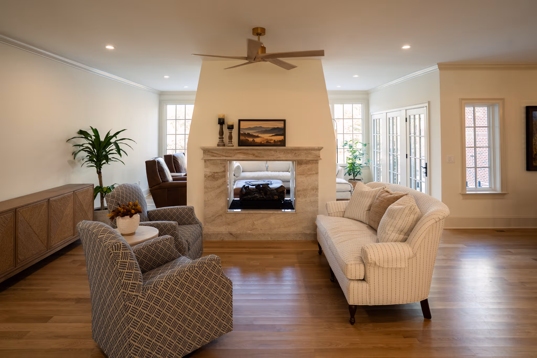 Metal barn with blue roof and cupolas partially obscured by green and orange autumn leaves.