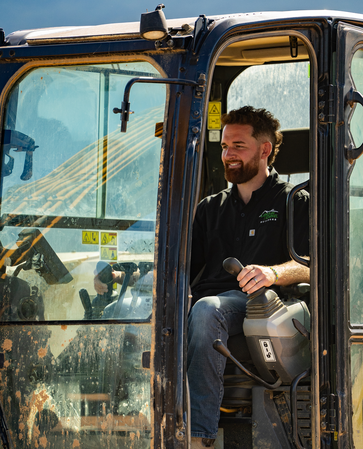 Two men reviewing architectural blueprints on a wooden table in a room with green walls and a window.