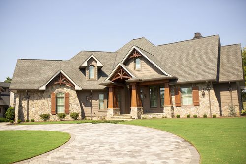 A masterfully crafted custom residence that pairs a grand, multi-textured stone and shingle exterior with sophisticated, warm tone interior living spaces.