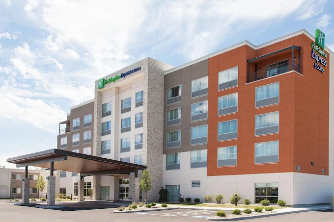 Exterior view of a modern four-story Holiday Inn Express hotel building with a covered entrance and parking area.