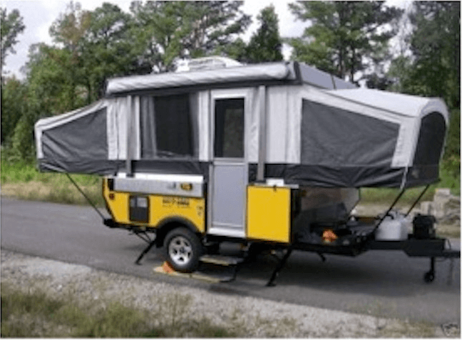 Yellow pop-up camper trailer with gray fabric sides set up on a roadside with trees in the background.