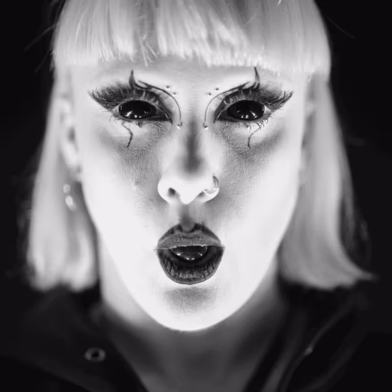 Portrait serré d’une artiste du Cabaret Décadent, maquillage théâtral noir et blanc, yeux soulignés de traits exagérés.