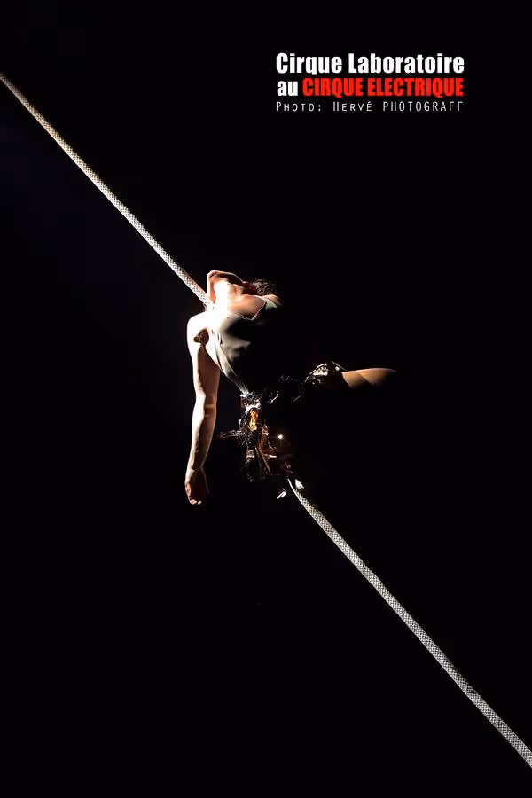 Cirque Électrique Laboratoire funambule Paris - artiste femme sur fil tendu, équilibre acrobatique, éclairage minimaliste contraste, performance aérienne nocturne, corps en suspension diagonale, spectacle contemporain poétique, photo Hervé Photograff
