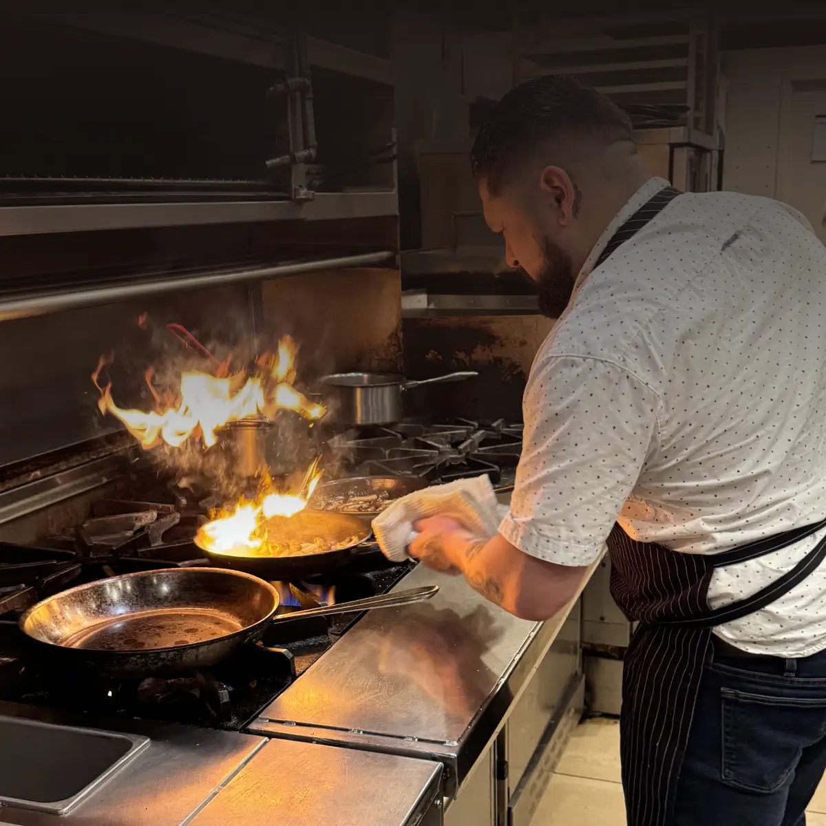 Chef Steve Ramirez working the sauté station, skillfully cooking over high heat and showcasing his expertise in the kitchen.