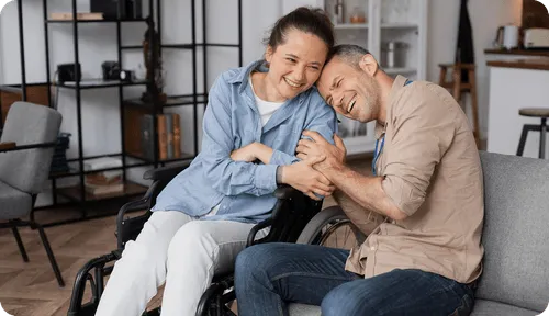 A man in a wheel chair hugging a woman.