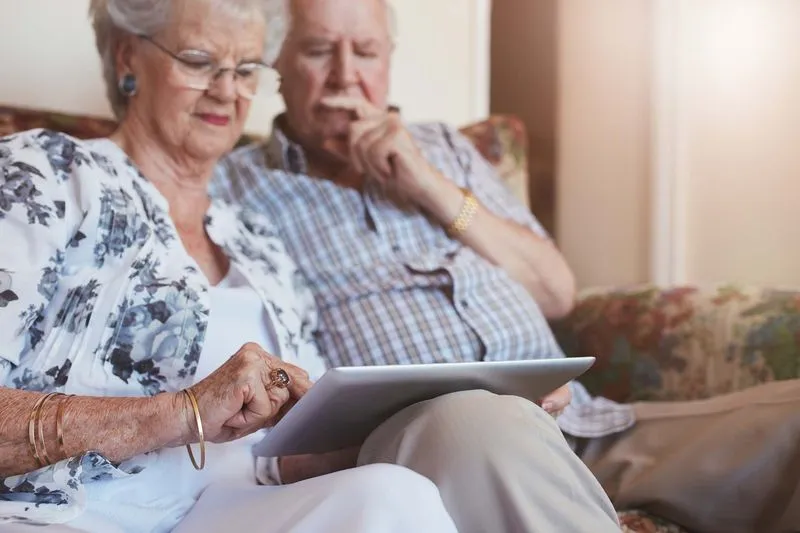 Elderly couple sitting together using a tablet at home