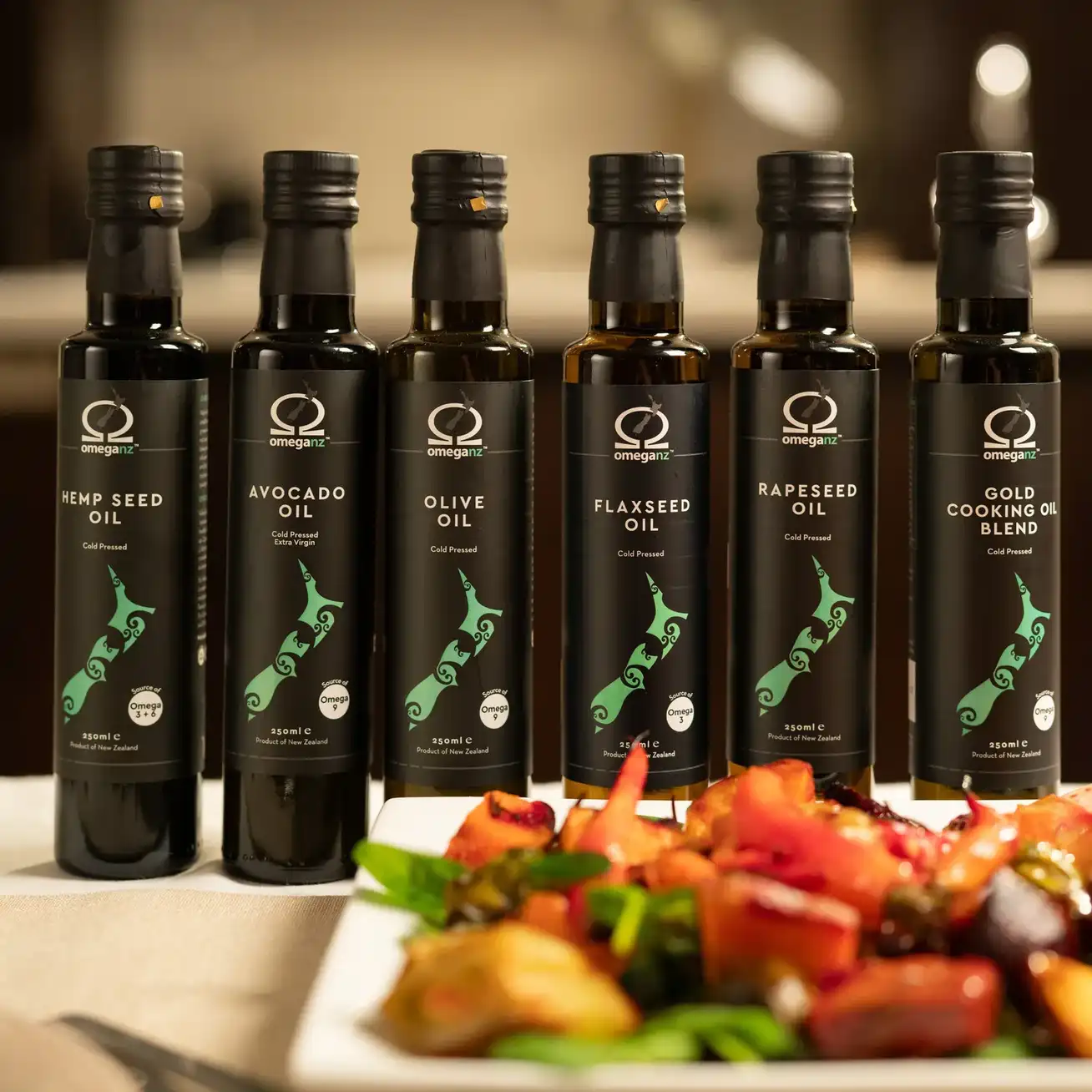 OmegaNZ bottled oil range sitting on a table behind roast vegetable salad