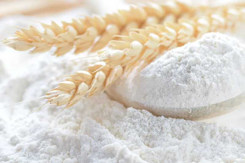 Close up of wheat stalks sitting on top of flour