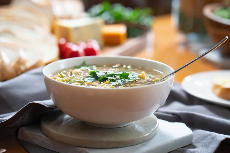 White bowl of soup with pearl barley, peas and lentils