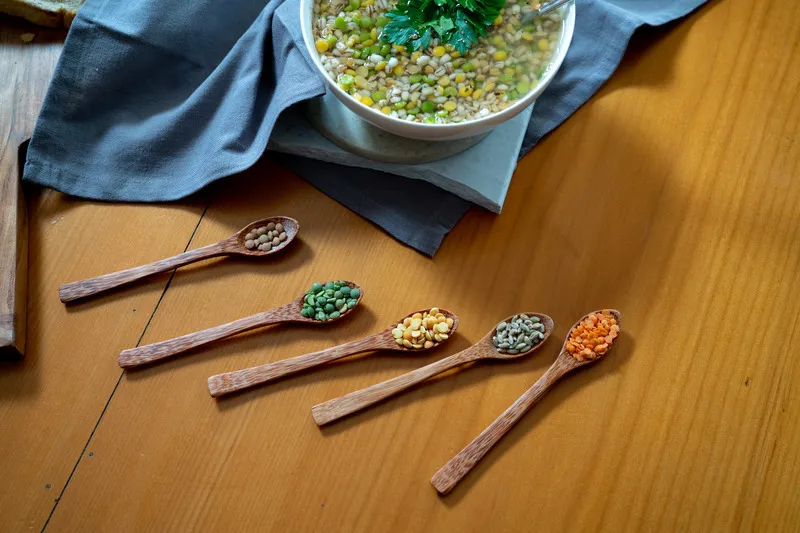 Bowl of soup, with yellow lentils and other pulses in wooden spoon