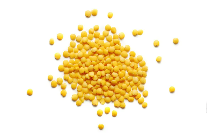 Yellow lentils in a pile on white background