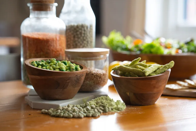 Marrowfat peas in a pile, with wasabi peas and pea chips in a bowl