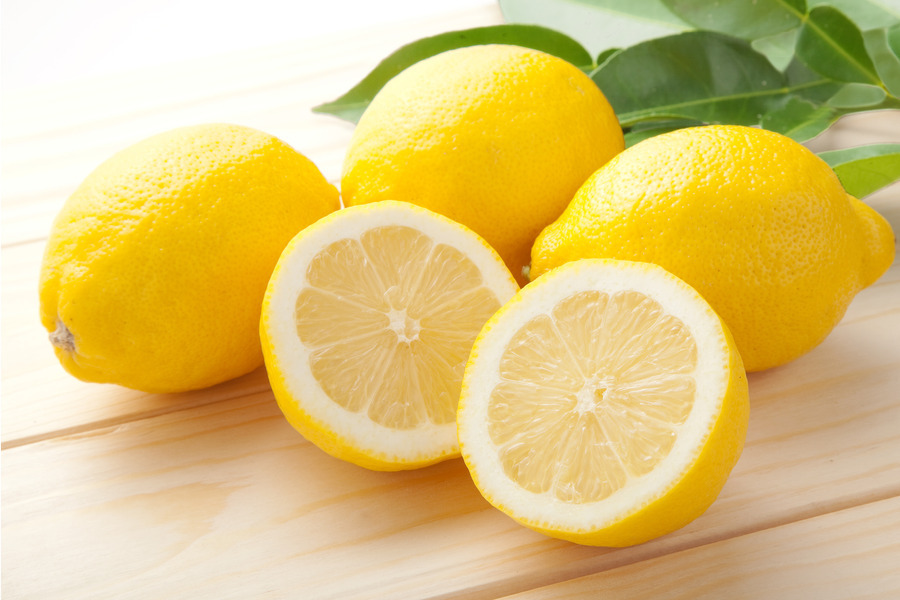 Cut lemon surrounded by more lemons on a wooden table