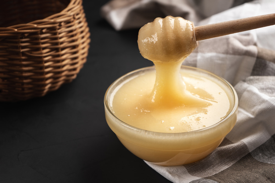 Clover honey in a small glass bowl with wooden dipper